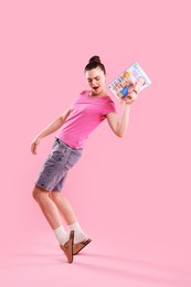 Photo of Woman with lifestyle magazine on pink background