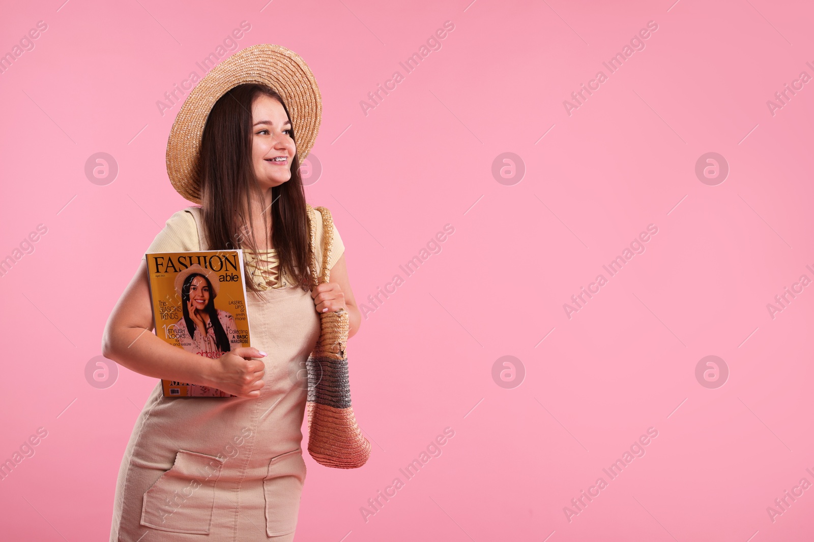 Woman with fashion magazine and bag on pink background, space for text Photo of Woman with fashion magazine and bag on pink background, space for text