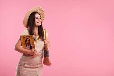 Photo of Woman with fashion magazine and bag on pink background, space for text