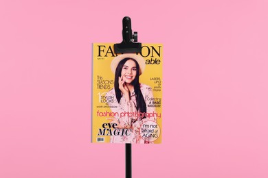 Photo of Fashion magazine on stand on pink background