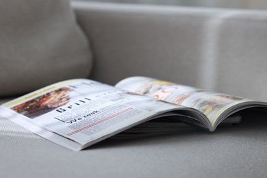 Photo of Lifestyle magazines on sofa indoors, closeup view