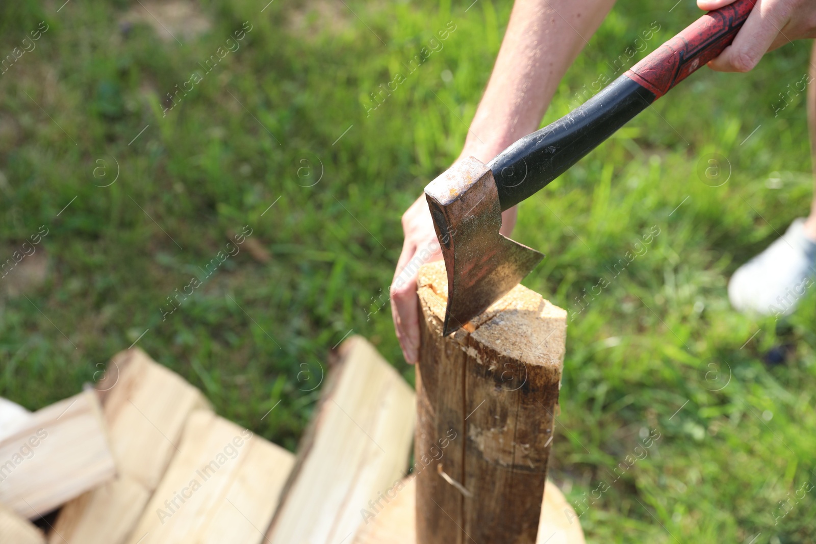 Man chopping firewood with axe outdoors, closeup. Space for text Photo of Man chopping firewood with axe outdoors, closeup. Space for text