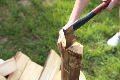 Photo of Man chopping firewood with axe outdoors, closeup. Space for text