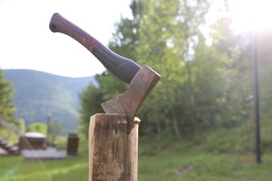 Photo of Metal axe on wooden log outdoors, closeup. Space for text