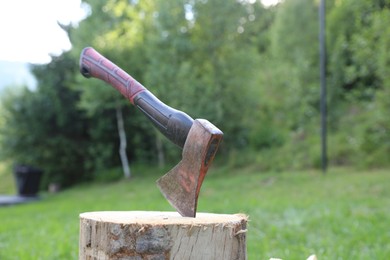 Photo of Metal axe and wooden log outdoors, closeup