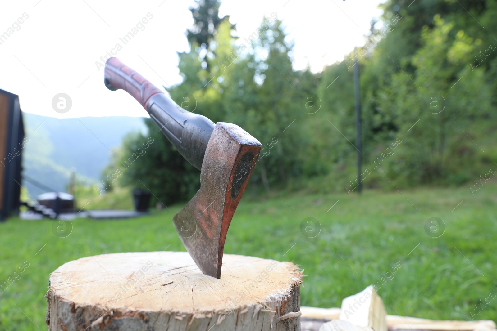 Metal axe, chopped firewood and wooden log outdoors Photo of Metal axe, chopped firewood and wooden log outdoors