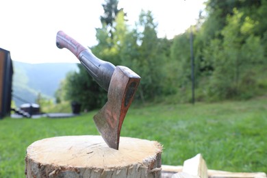 Photo of Metal axe, chopped firewood and wooden log outdoors