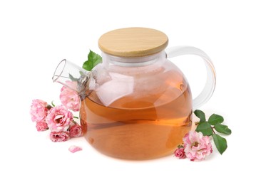 Photo of Tasty rose tea in glass teapot, flowers and leaves isolated on white