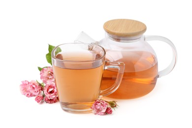 Photo of Tasty rose tea in glass cup, teapot and flowers isolated on white