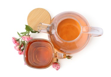 Photo of Tasty rose tea in glass cup, teapot and flowers isolated on white, top view