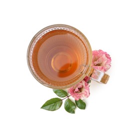 Photo of Tasty rose tea in glass cup, flowers and sprig with leaves isolated on white, top view
