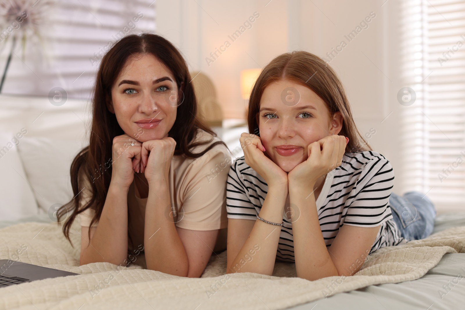 Photo of Portrait of mother and her teenage daughter on bed at home