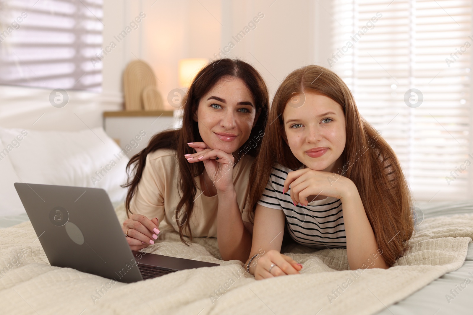 Photo of Portrait of mother and her teenage daughter on bed at home
