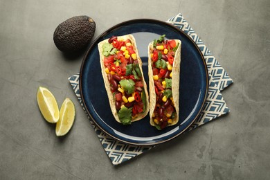 Photo of Tasty vegetarian tacos with beans, vegetables, avocado and lime on grey table, flat lay