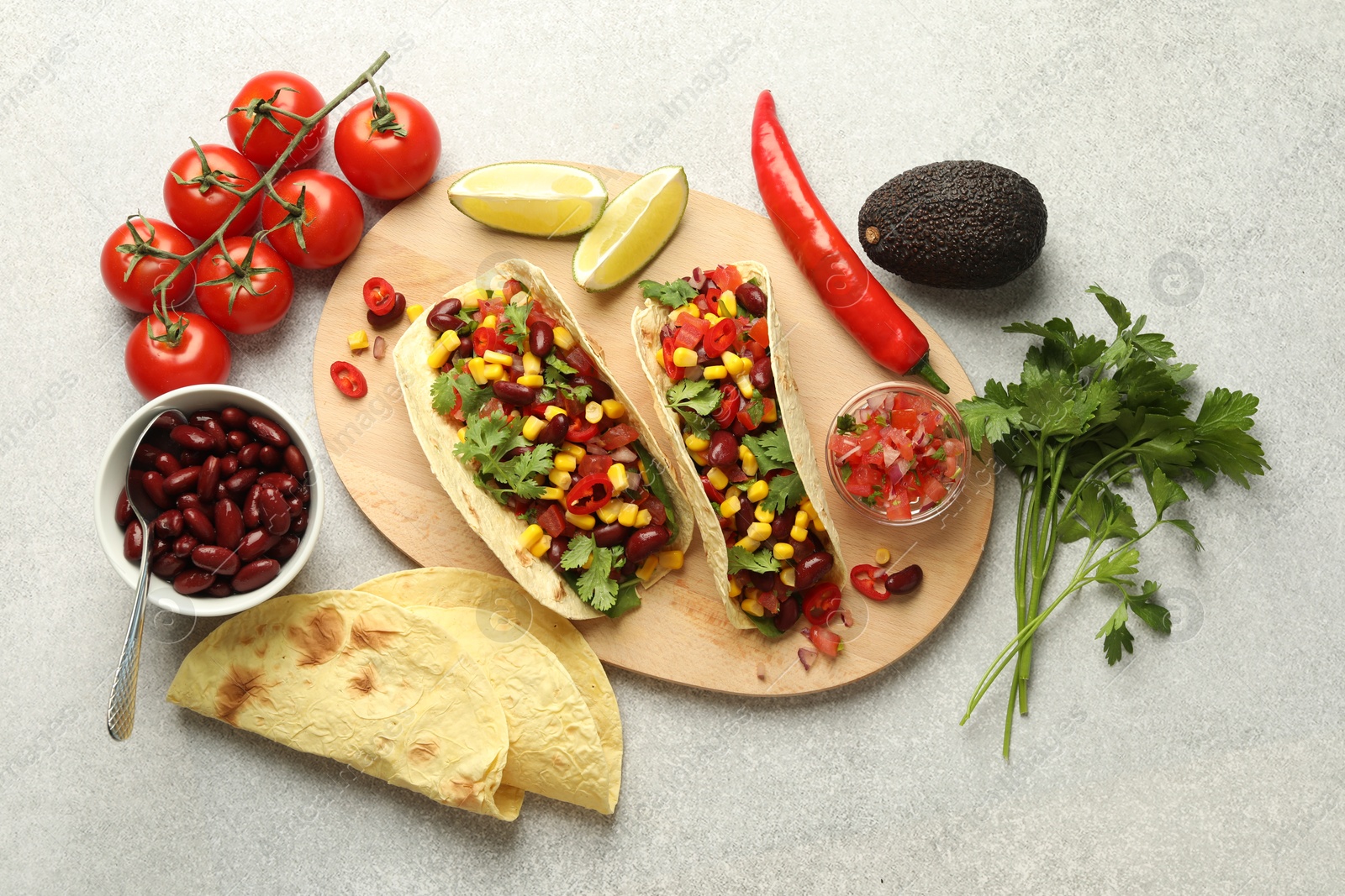 Photo of Tasty vegetarian tacos and ingredients on light grey table, flat lay