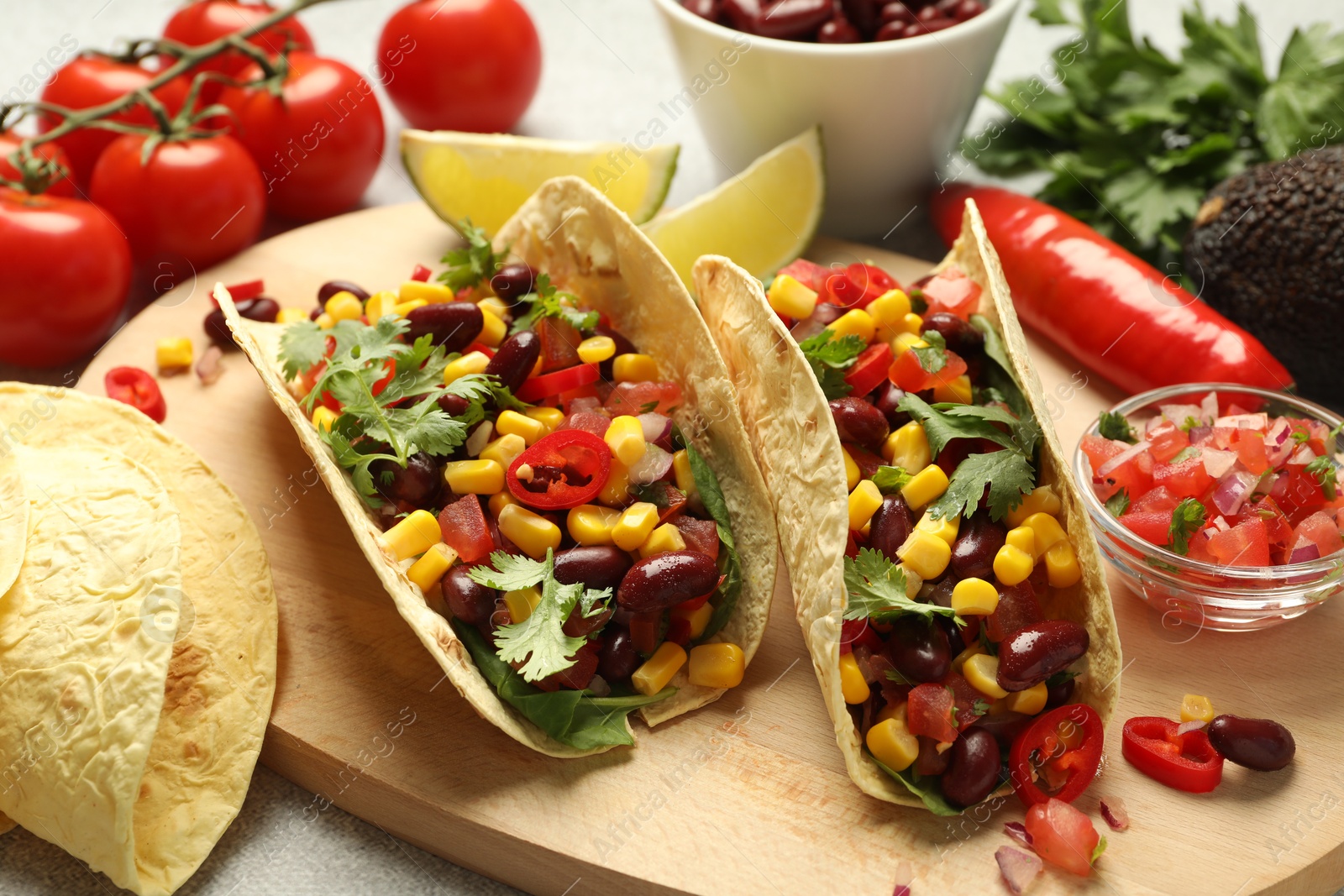 Photo of Tasty vegetarian tacos and ingredients on table, closeup