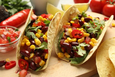 Photo of Tasty vegetarian tacos and ingredients on table, closeup