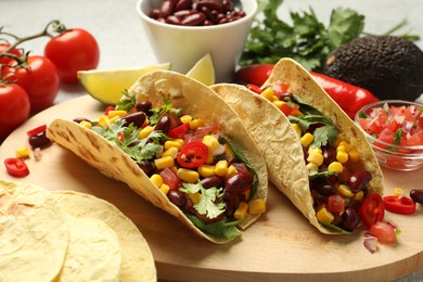 Photo of Tasty vegetarian tacos and ingredients on table, closeup