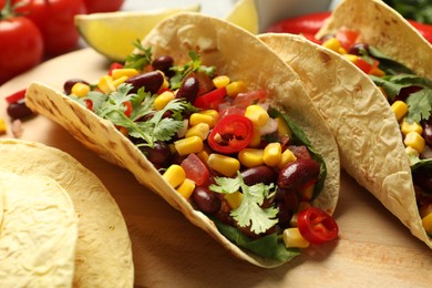 Photo of Tasty vegetarian tacos and ingredients on table, closeup