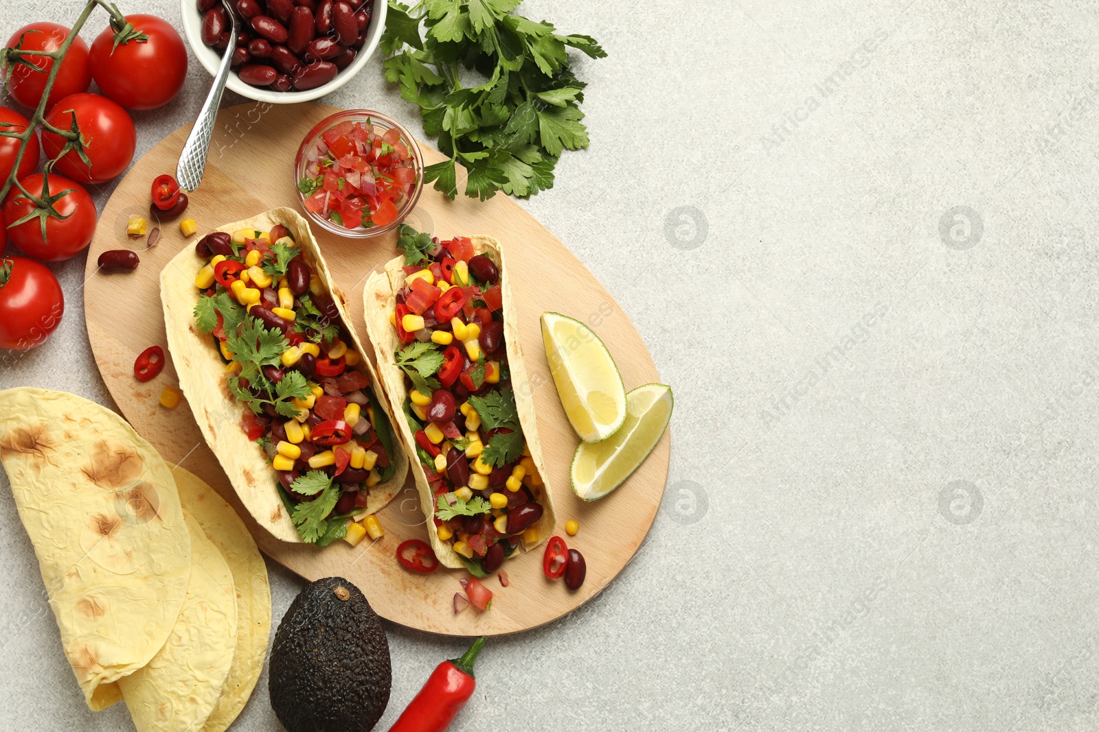 Photo of Tasty vegetarian tacos and ingredients on light grey table, flat lay. Space for text
