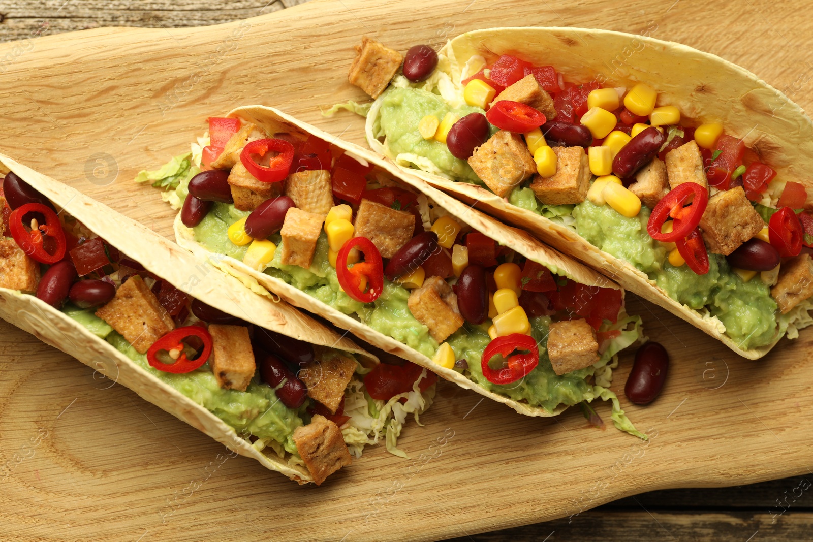 Photo of Tasty vegetarian tacos with beans, tofu and vegetables on table, top view