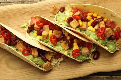 Photo of Tasty vegetarian tacos with beans, tofu and vegetables on table, top view