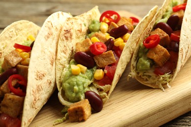 Photo of Tasty vegetarian tacos with beans, tofu and vegetables on table, closeup