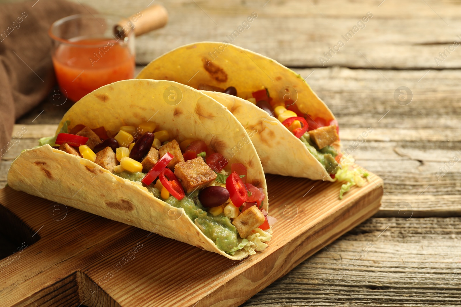 Photo of Tasty vegetarian tacos served with sauce on wooden table, closeup