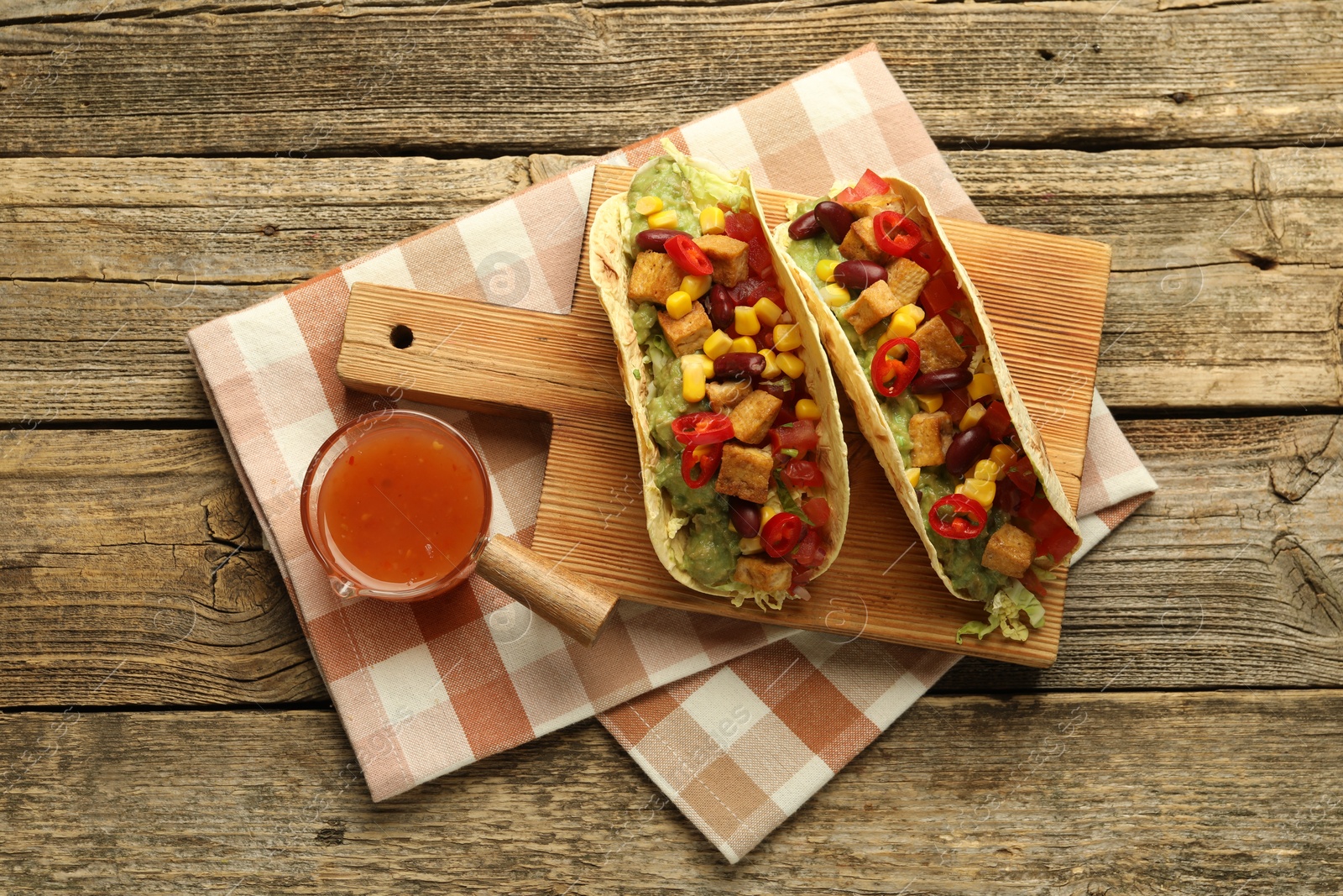 Photo of Tasty vegetarian tacos served with sauce on wooden table, flat lay