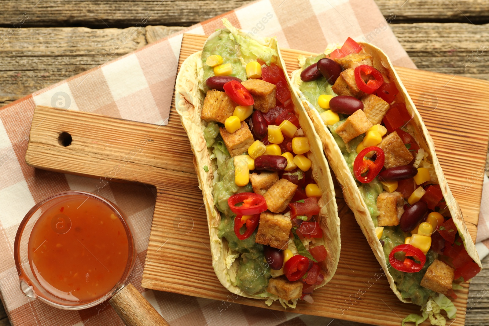 Photo of Tasty vegetarian tacos served with sauce on wooden table, flat lay