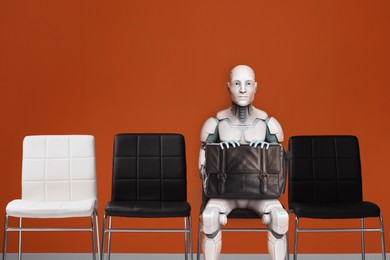 Image of Robot with bag sitting on chair and waiting for job interview. Replacing human workers with artificial intelligence