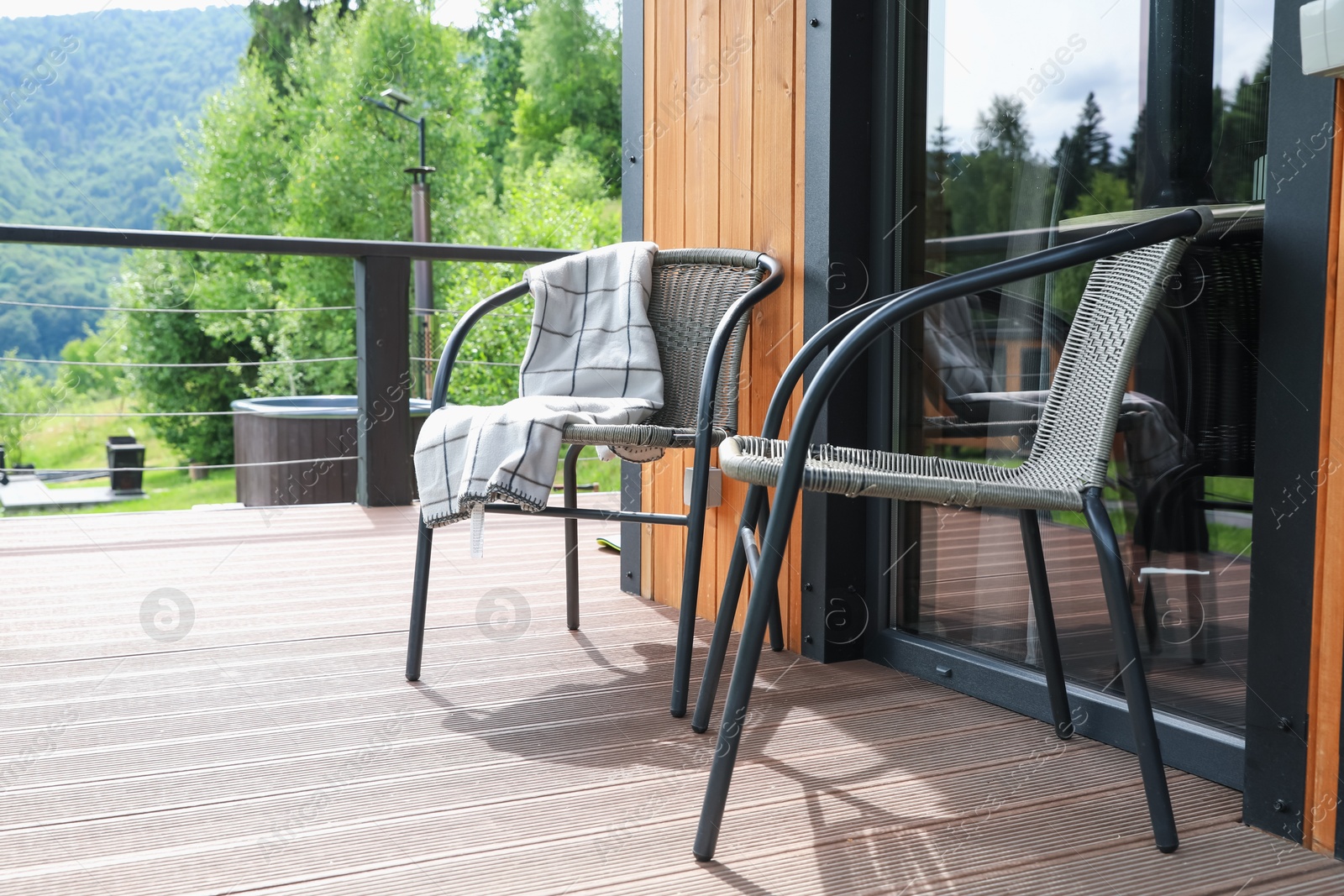 Photo of Rattan chairs and plaid on outdoor terrace at luxury resort in mountains