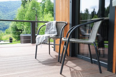 Photo of Rattan chairs and plaid on outdoor terrace at luxury resort in mountains