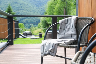 Photo of Rattan chairs and plaid on outdoor terrace at luxury resort in mountains