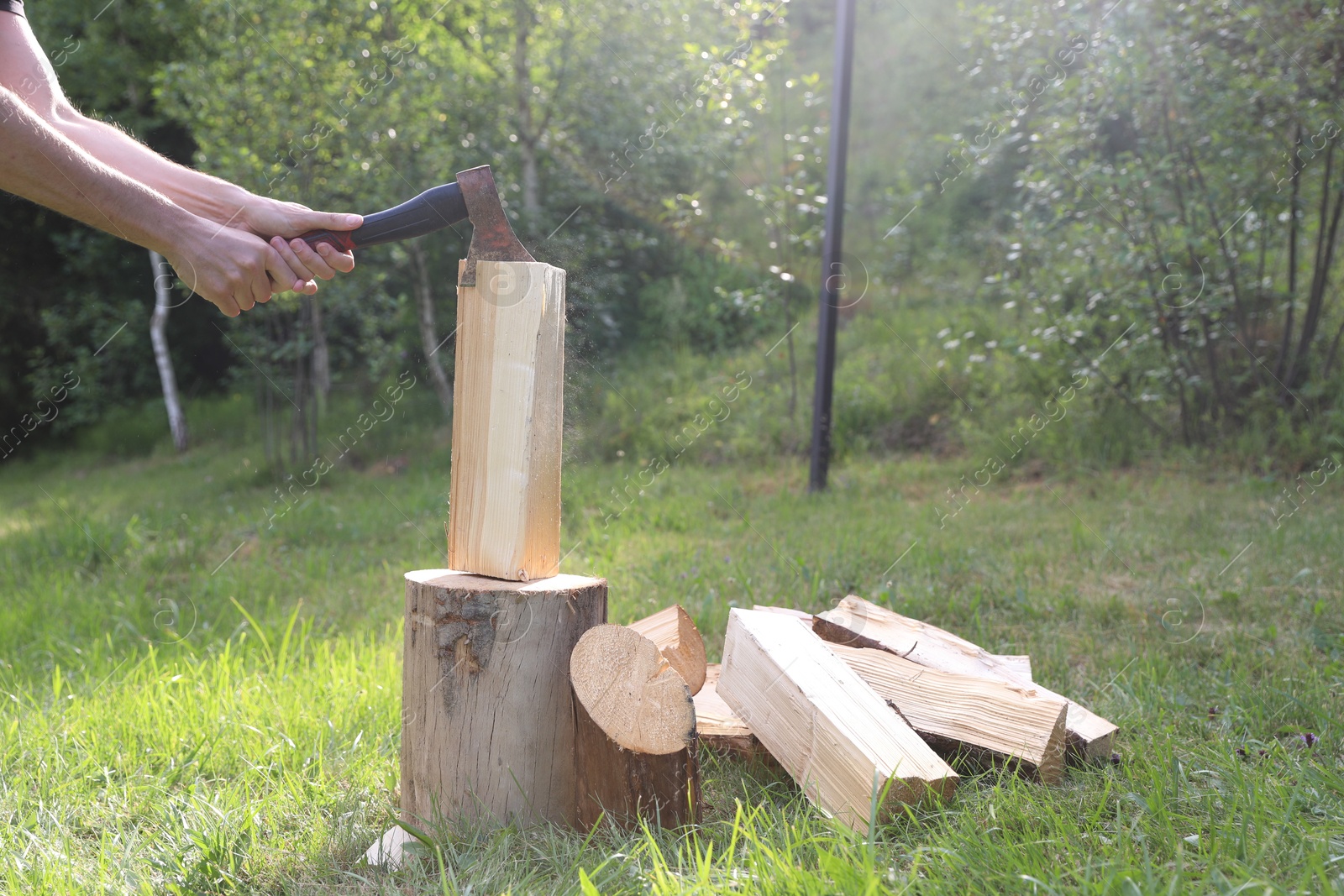 Photo of Man chopping firewood with axe outdoors, closeup