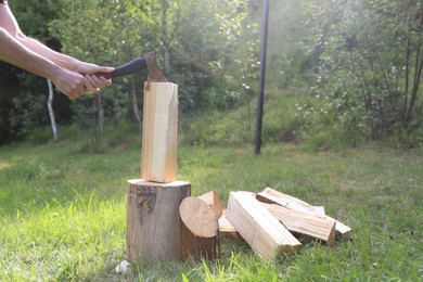 Photo of Man chopping firewood with axe outdoors, closeup