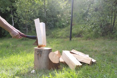 Photo of Man chopping firewood with axe outdoors, closeup