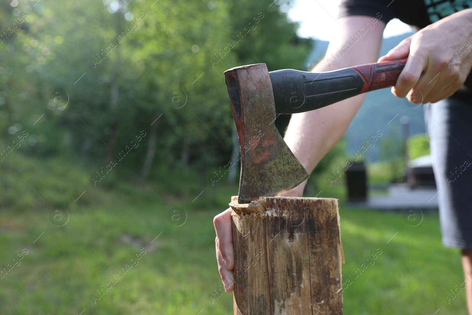 Photo of Man chopping firewood with axe outdoors, closeup. Space for text