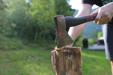 Photo of Man chopping firewood with axe outdoors, closeup. Space for text