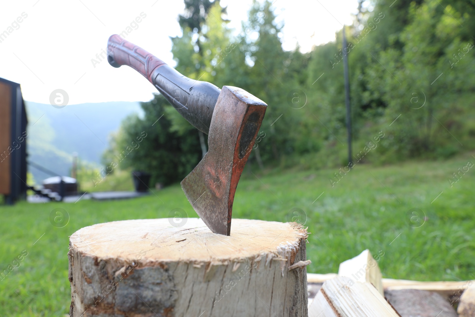 Metal axe, chopped firewood and wooden log outdoors Photo of Metal axe, chopped firewood and wooden log outdoors