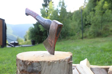 Photo of Metal axe, chopped firewood and wooden log outdoors