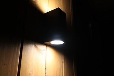 Photo of Stylish lamp on wooden wall of building, low angle view