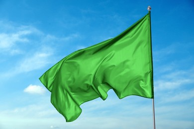 Image of Green flag waving against blue sky outdoors