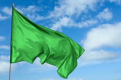 Image of Green flag waving against blue sky outdoors
