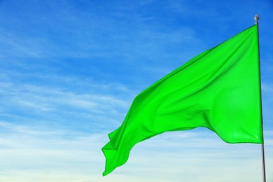Image of Green flag waving against blue sky outdoors