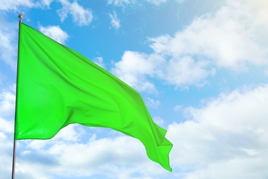 Image of Green flag waving against blue sky outdoors