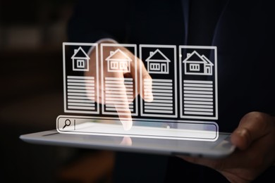 Image of Real estate agent using tablet computer, closeup. House icons and data above device. Searching for housing online