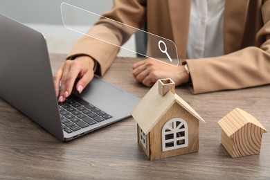 Image of Searching for housing online. Real estate agent using laptop at table with house models, closeup. Search bar above computer
