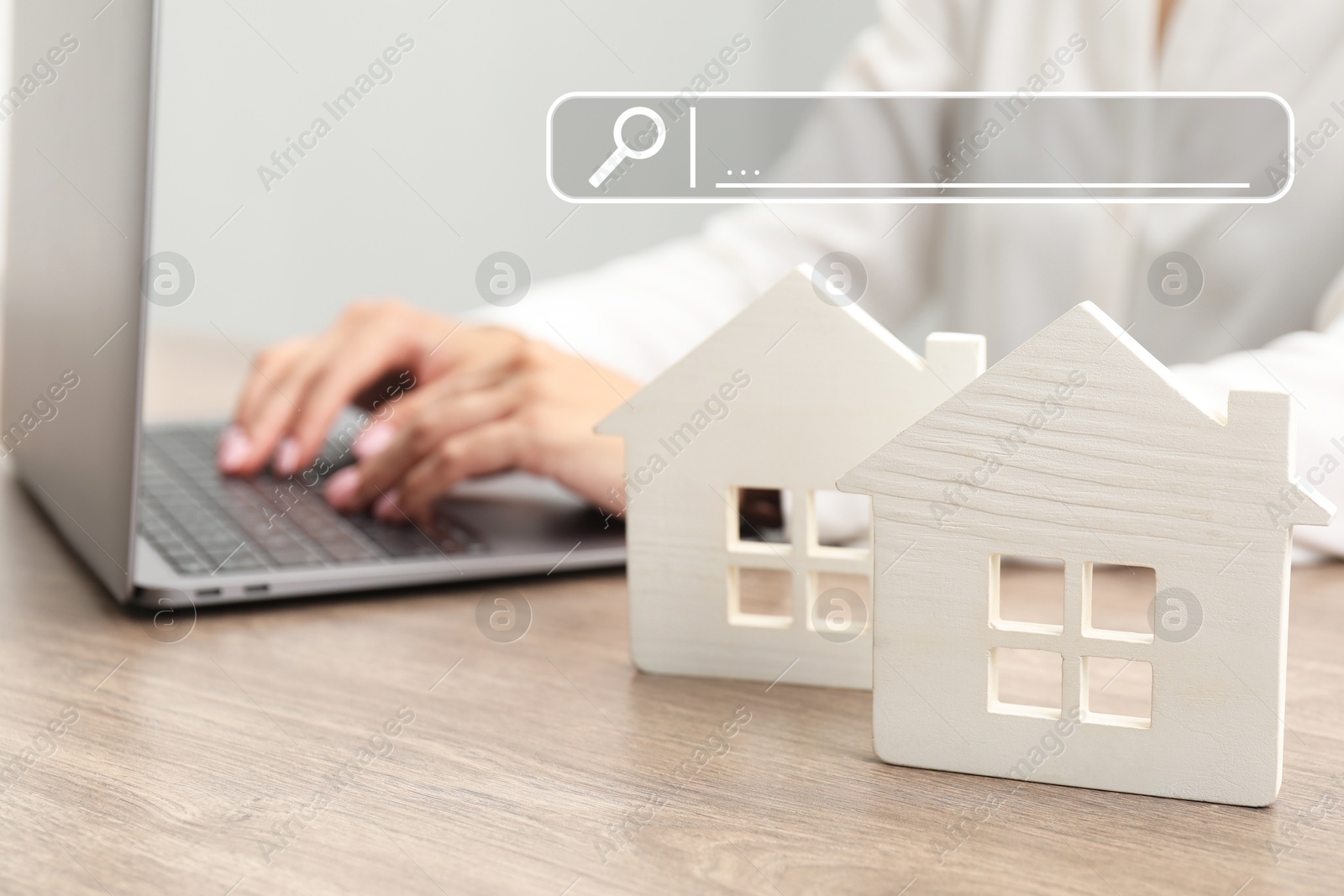 Image of Searching for housing online. Real estate agent using laptop at table, closeup. Search bar above house models