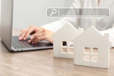 Image of Searching for housing online. Real estate agent using laptop at table, closeup. Search bar above house models